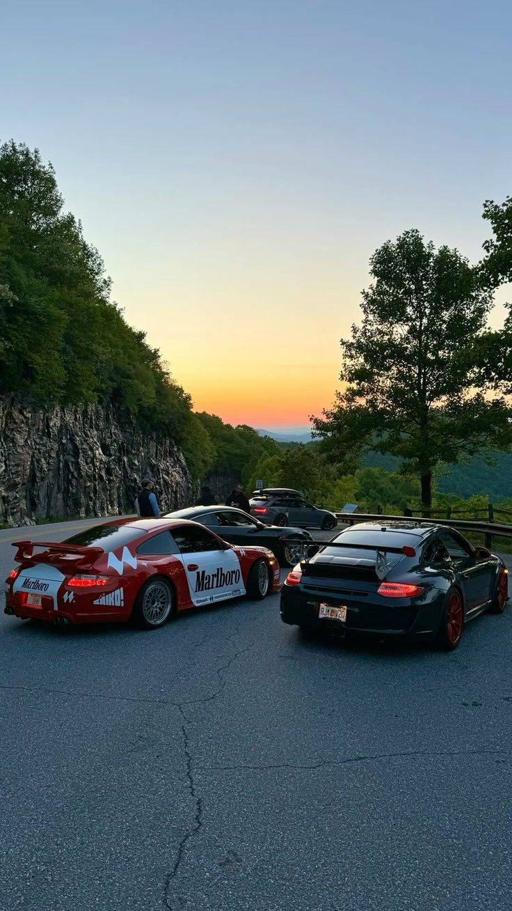 Performance cars gathered on a mountain road at golden hour